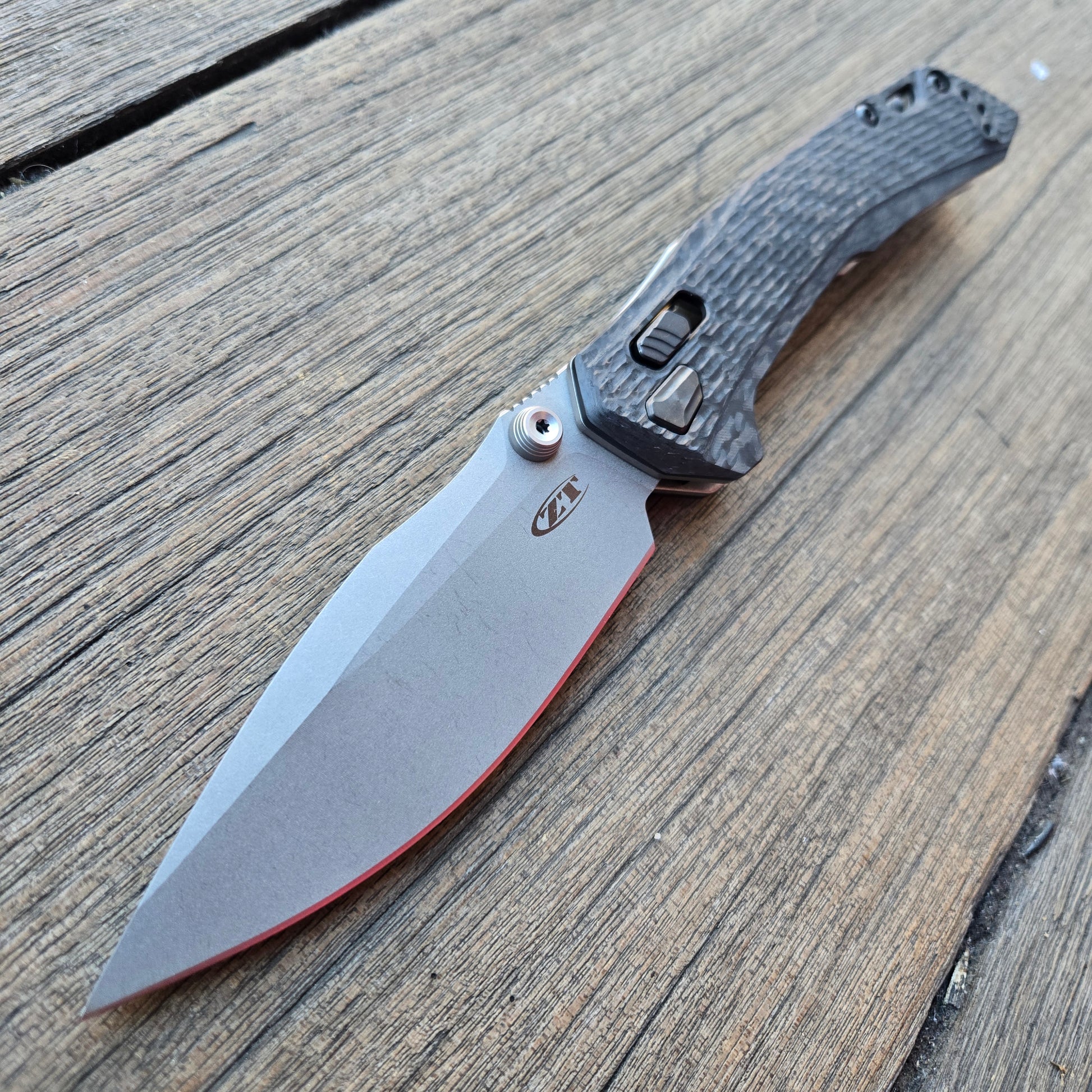 Folding knife with a textured handle on a wooden surface