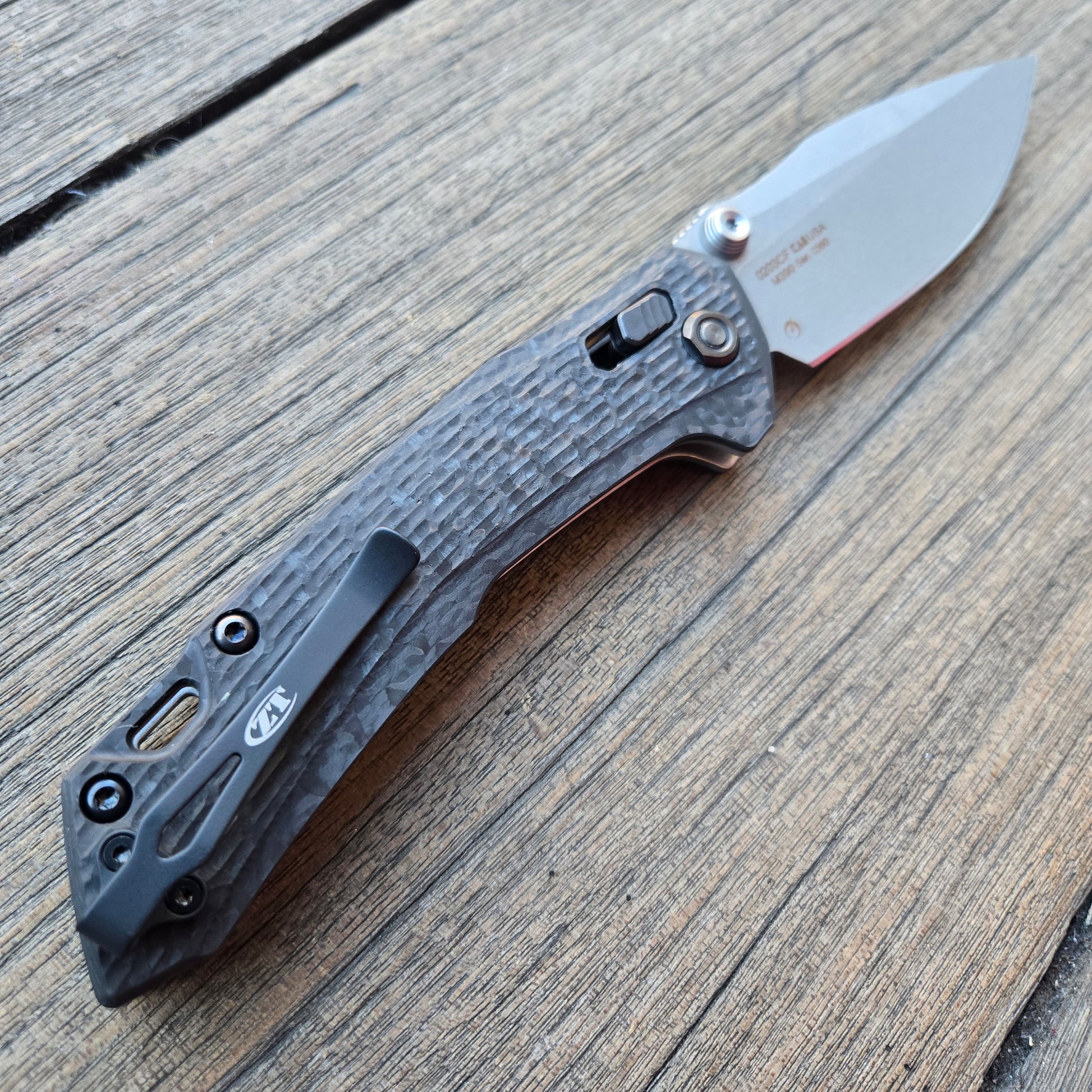 Folding knife with a textured handle on a wooden surface