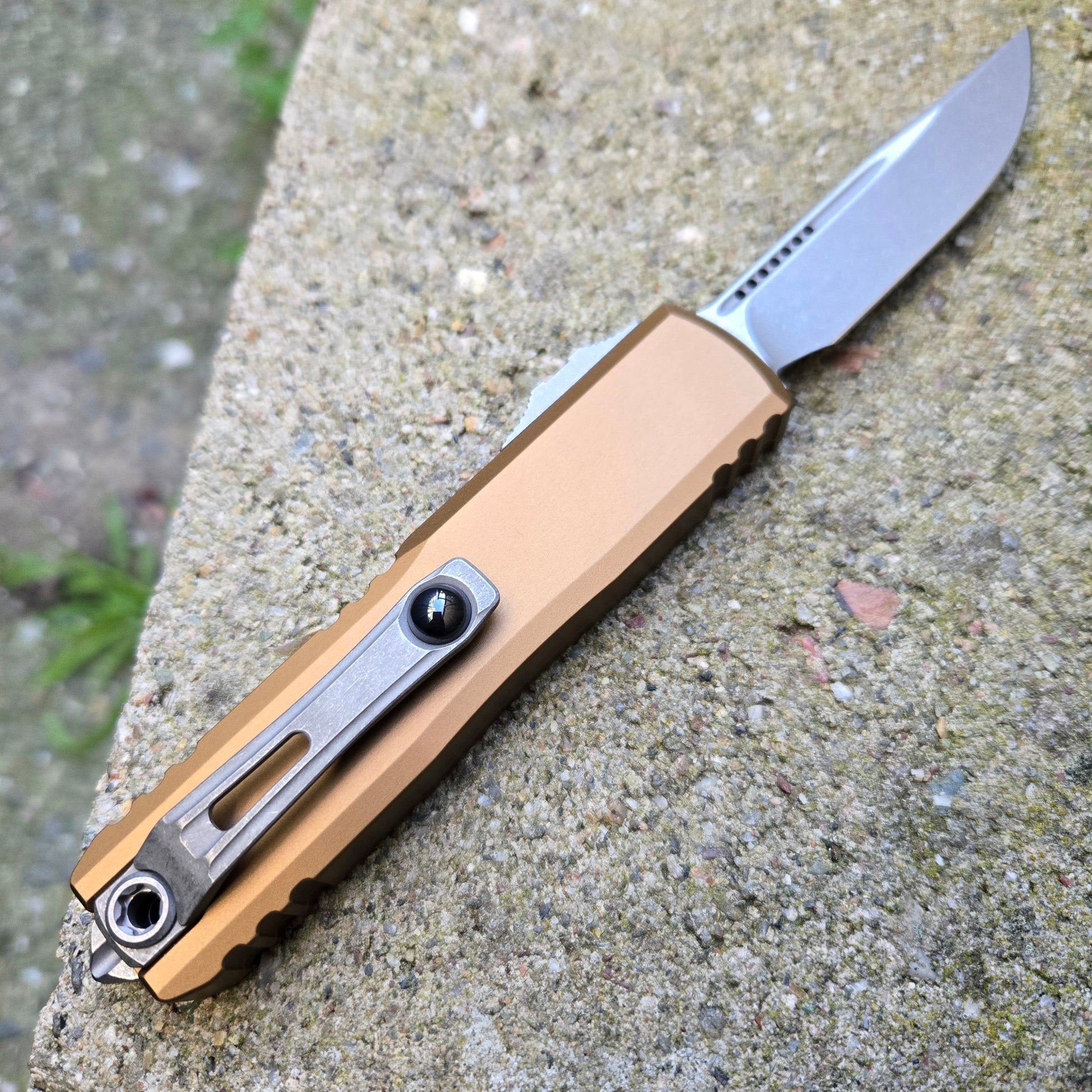 Folding knife with a tan handle on a concrete surface