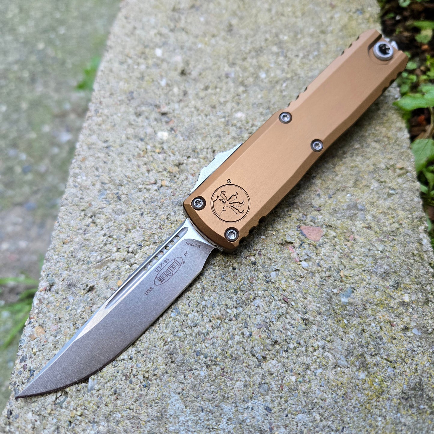 Folding knife with a tan handle on a concrete surface