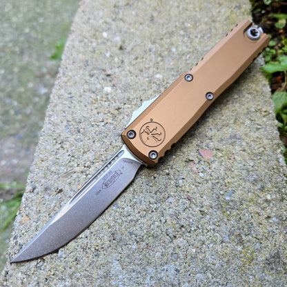 Folding knife with a tan handle on a concrete surface