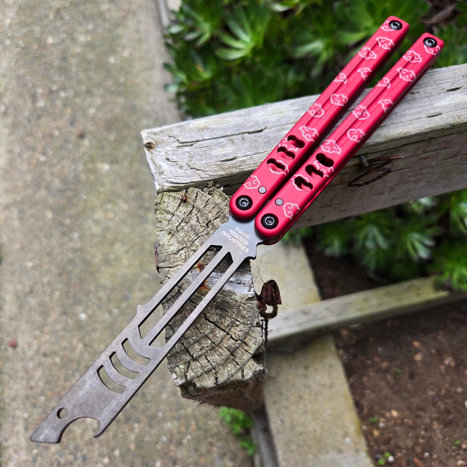 Multitool with red handle and silver blade on a wooden post