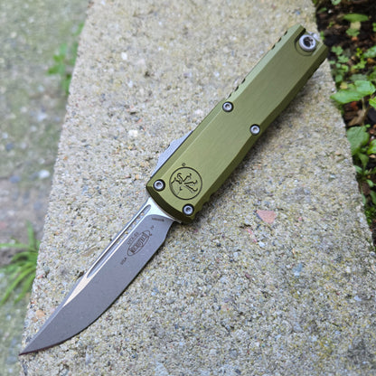 Green folding knife on a concrete surface