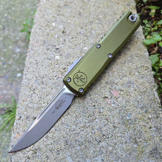 Green folding knife on a concrete surface