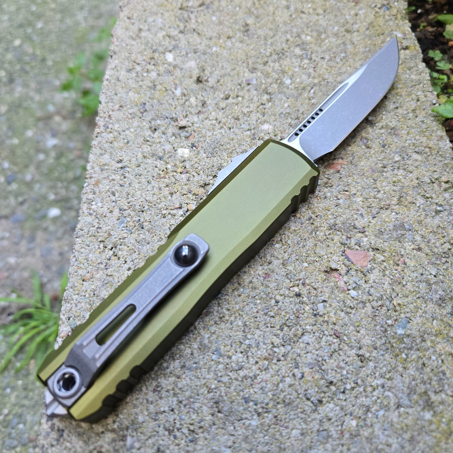 Folding knife with a green handle on a concrete surface