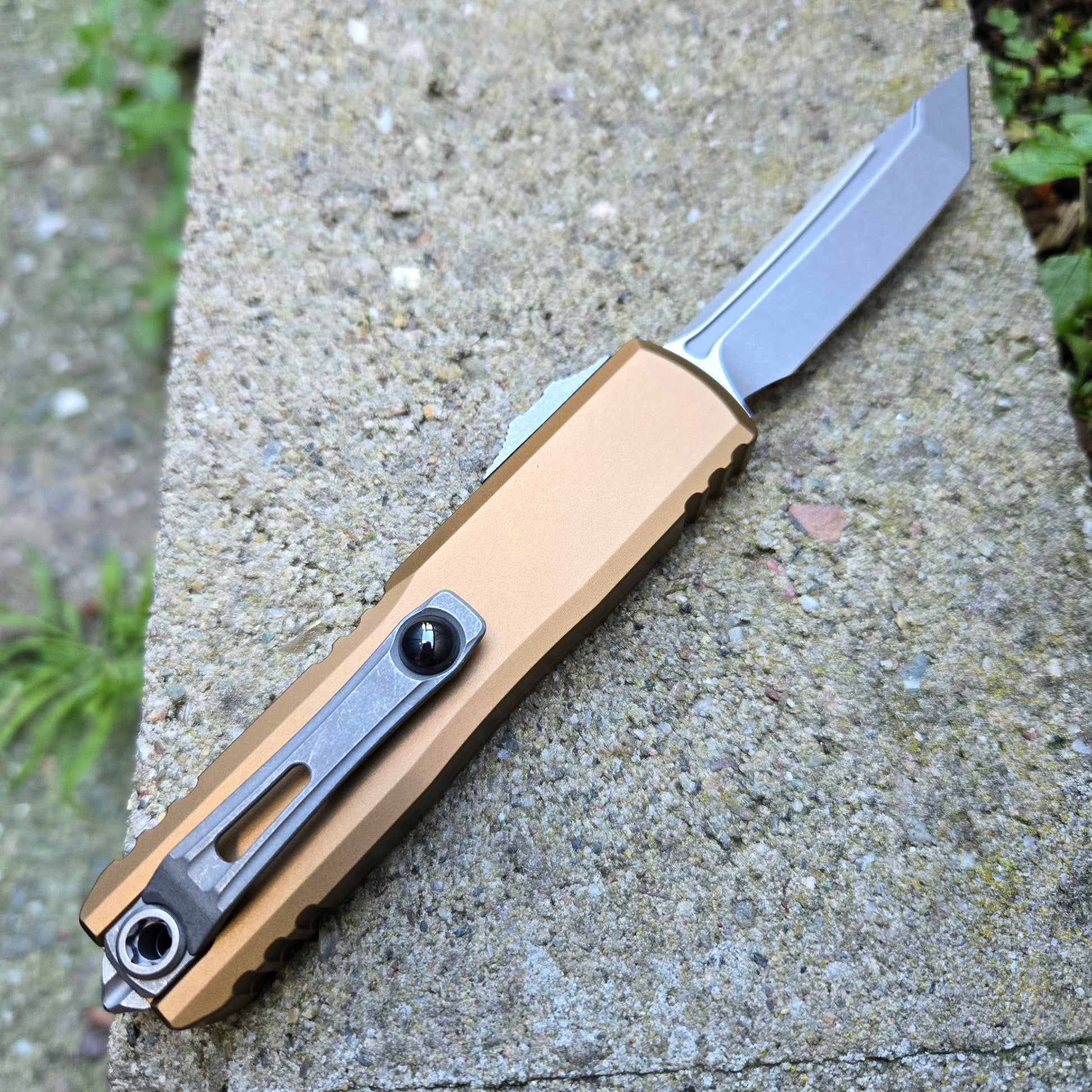 Folding knife with a metallic blade and brown handle on a concrete surface